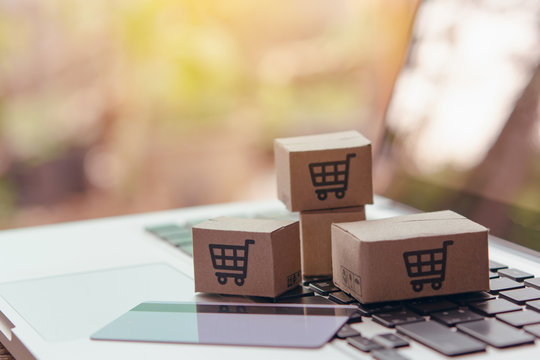 Online shopping - Paper cartons or parcel with a shopping cart logo and credit card on a laptop keyboard. Shopping service on The online web and offers home delivery...