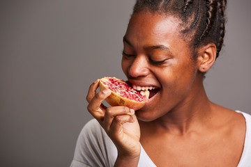 Studio portrait of a funny young African woman eating a salad. Fresh fruits and healthy diet concept.
