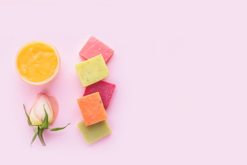 Open jar of cosmetic cream, soap and rose on pink background. Concept of natural spa cosmetics. Flat lay, top view, copy space .