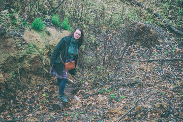 Informally dressed girl in a ravine covered with autumn leaves