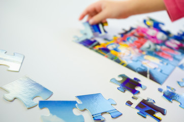 Close-up little girl collects puzzle at home at the table - 314896383