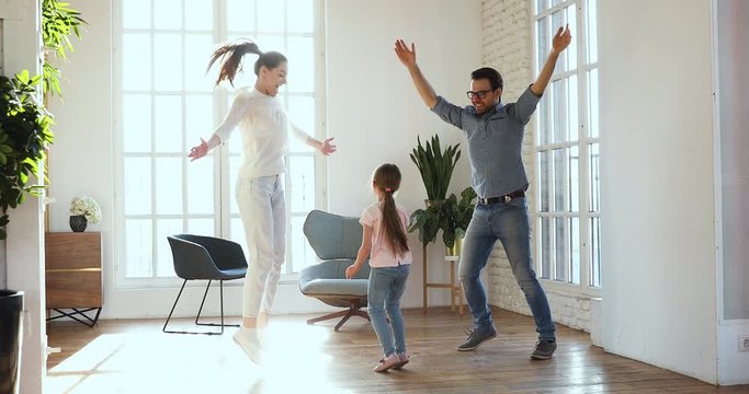 Active carefree parents and kid daughter dancing together at home