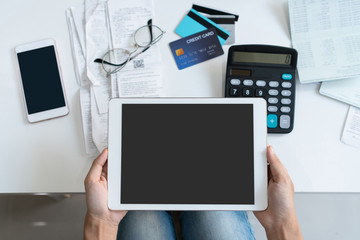 Pretty young Asian woman working with tablet to do home expenses and taxes in living room at home. Copy space, top view.