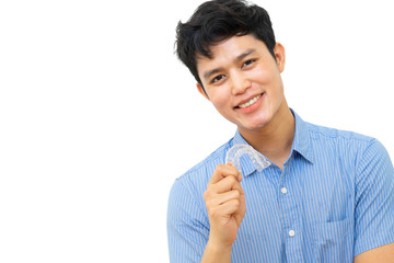 close up (isolated) young asian man smiling with hand holding dental aligner retainer (invisible) on white background of dental clinic for beautiful teeth treatment course concept	