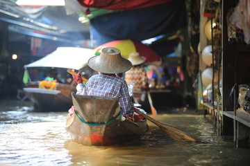 back view of  boat woman on the damnoen saduak floating market in thailand