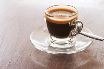 Glass of espresso on wooden table with copy space.
