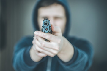 Crime or robbery concept: Man with black gun is aiming with his weapon