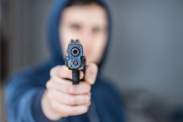 Crime or robbery concept: Man with black gun is aiming with his weapon