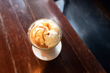 Ice latte coffee with scoop of vanilla ice cream and caramel syrup on top; top view.