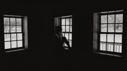 Femme regardant par la fenêtre en noir et blanc&