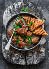 Fried meatballs in a frying pan on a dark background, top view