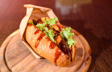 Big tasty hot dog on a wooden tray on the table. Unhealthy food.