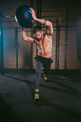 Details of a athletic guy using a cross fit ball to do his hard training workout exercises in a...