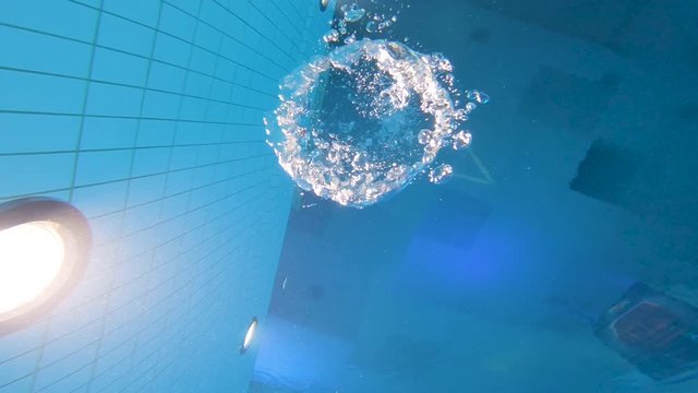Blowing bubble rings under the water in an indoor pool and watching them float to the surface