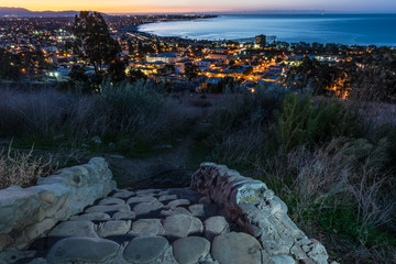 Lights of coastal city of Ventura viewed over stone cut staircase steps as dawn begins to break in the sky.