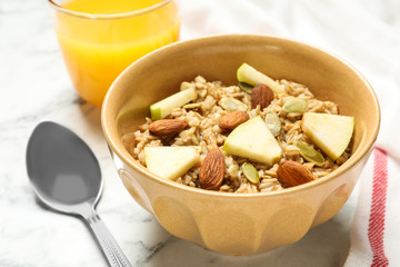 Tasty oatmeal with apples and almonds on marble table, closeup. Healthy breakfast