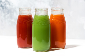 colorful vegetable juices in bottles on white table, closeup