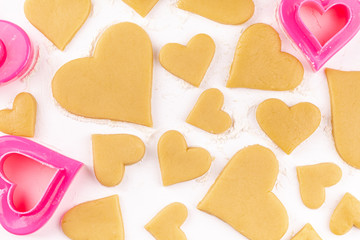 Obraz premium A Lot of Raw Homemade Heart Shaped Cookies with Pink Cookie Cutter and Flour on the White Table. Concept of Happy Valentines Day and Birthday. Top View