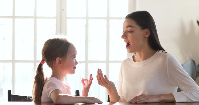 Caring mom speech therapist teaching preschooler girl correct pronunciation