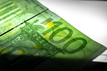 100 Euro banknote. Lying in the ultraviolet to verify the authenticity of banknotes. Close-up