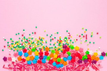 Obraz na płótnie Canvas Colorful confectionery topping on a plain pink background with copy space for text, birthday bright background. Festive background with colored sweets.