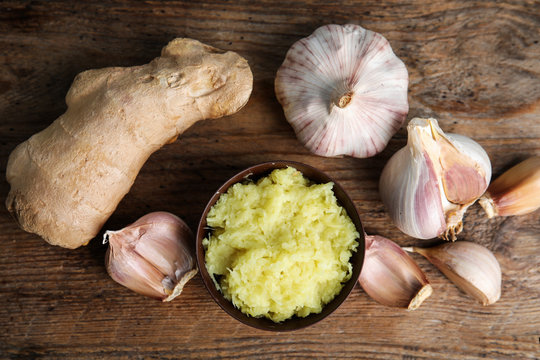 Fresh garlic and ginger on wooden table, flat lay. Natural cold remedies