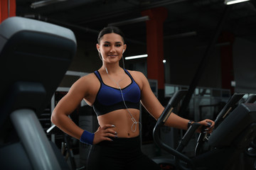 Fototapeta na wymiar Young woman working out on elliptical trainer in modern gym