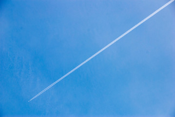 Avion dans le ciel bleu laissant une trace blanche. Plane in the blue sky leaving a white trace.