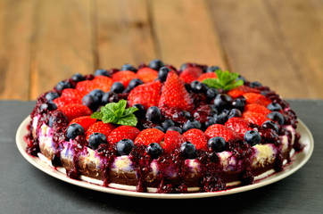 Fresh strawberries, blueberries and cherry jam tart on slate slab and wooden background.