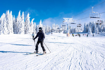 Young man skiing in mountain ski resort with beautiful winter landscape in the background