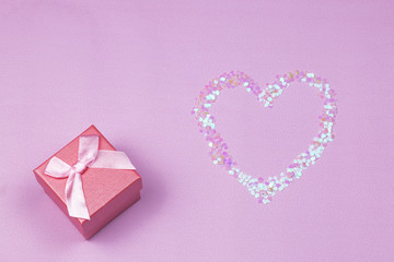 Valentine’s day composition. Heart made of confetti and pink gift box on pink background. Part of set.