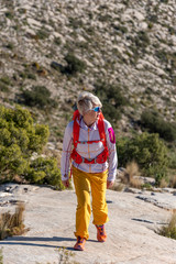 Woman hikes along ridgecrest walks up hill, El Divino mountain, Alicante province, Costa Blanca, Spain