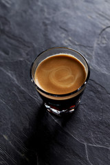 Coffee in glass cup on dark stone background. Close up. 