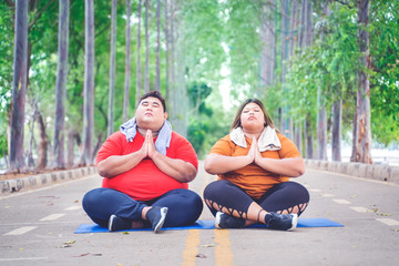 Fat couple meditating while relaxing on the road