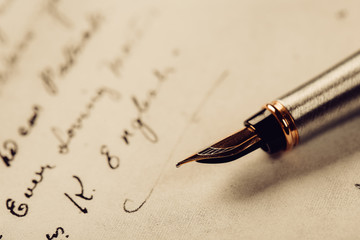 Fototapeta premium Fountain pen on an ancient handwritten letter. Old story. Retro style.