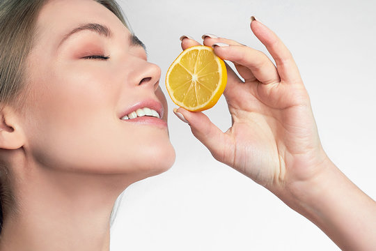 portrait of pretty young woman holding slices of orange, facial care.