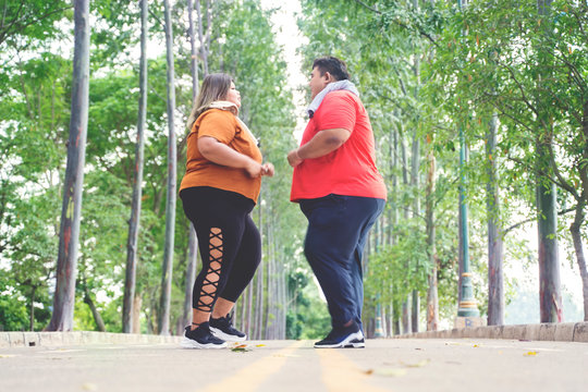 Fat couple turning back while jogging at the park
