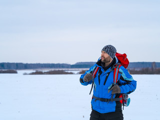 Winter portrait of a male tourist with backpack.