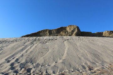 Fototapeta na wymiar Gray sand on a background of blue sky