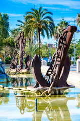 huge Large old ship anchor as a park decoration with a large fountain, iron scrap from an old ship, use as a fountain decoration, Spanish design, an old screeching ship chain, water in tank, blue sky