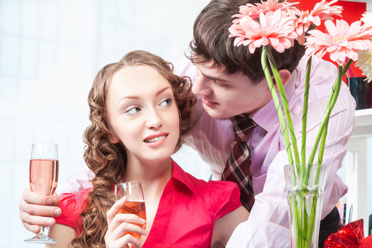 A young man, an employee of the company shows courtship to his colleague-a young woman with curly hair. The man gave flowers and offers to drink champagne in the office on Valentine's day. Flirting, 