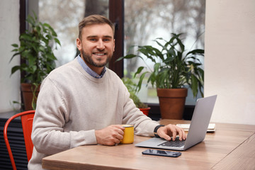 Male blogger working with laptop at table in cafe