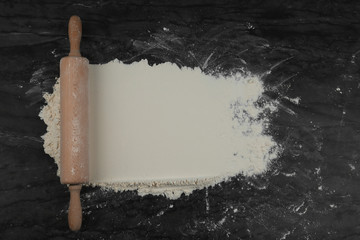 Flour and rolling pin on grey marble table, flat lay with space for text