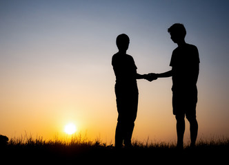 Silhouette of lovely couple holding by hands on beautiful sunset