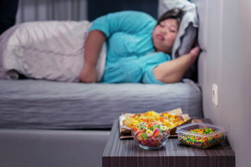 Obraz na płótnie Canvas Fat woman sleeping while her fast foods lying