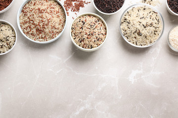 Different sorts of rice on light grey marble table, flat lay. Space for text