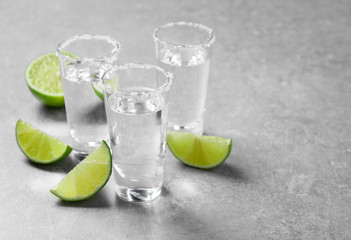 Mexican Tequila shots with salt and lime slices on grey table