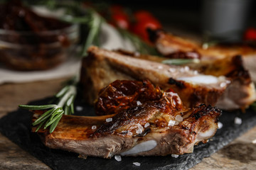 Tasty grilled ribs with rosemary on wooden table, closeup