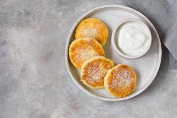 Cottage cheese pancakes or syrniki with sour cream on hand-made ceramic plate