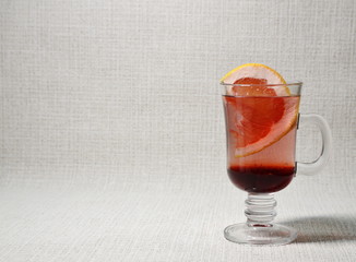 On a white background is a glass cup with a refreshing, tonic, fresh, cold drink of grapefruit, sliced ​​appetizing slices of fruit.